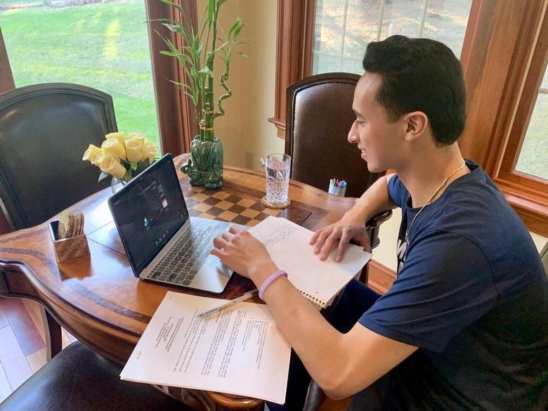 Male student learning remotely on laptop.