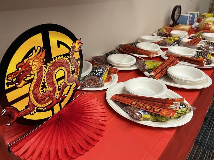 A table decorated for Lunar New Year including paper dragons, plates, chopsticks and a red tablecloth.